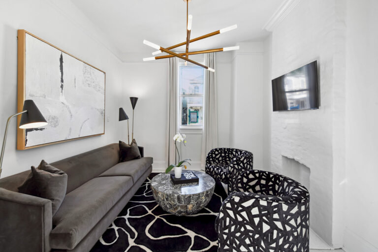 Uptown renovation living room with a gray sofa, black-and-white patterned chairs and a geometric brass chandelier