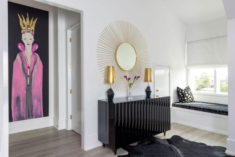 Pass Christian home entry with a black console, gold sunburst mirror, colorful portrait and window seat
